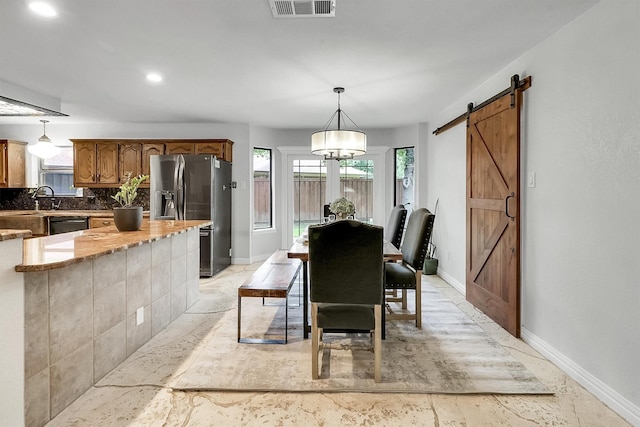 dining area with a barn door, an inviting chandelier, and sink