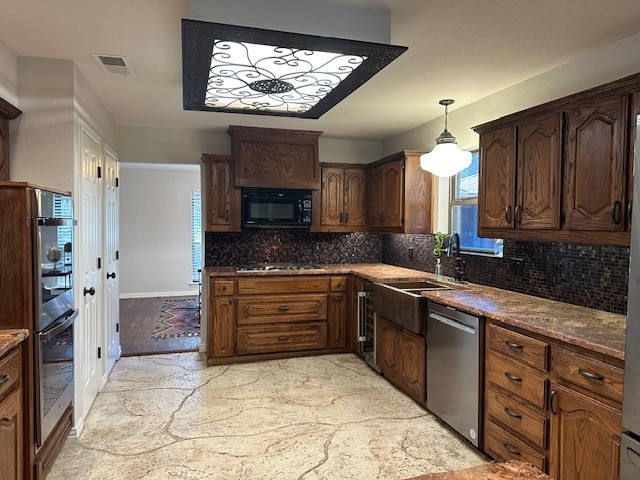 kitchen featuring stone counters, sink, decorative light fixtures, decorative backsplash, and appliances with stainless steel finishes