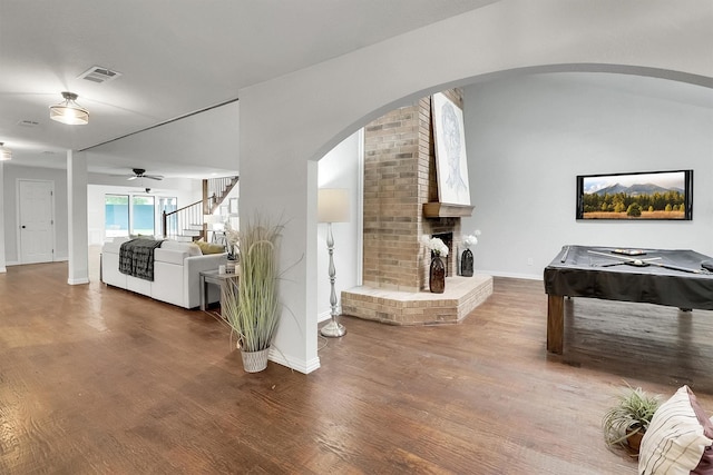 living room with hardwood / wood-style floors, a brick fireplace, ceiling fan, and pool table