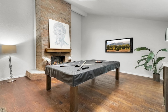 recreation room with pool table, wood-type flooring, vaulted ceiling, and a brick fireplace