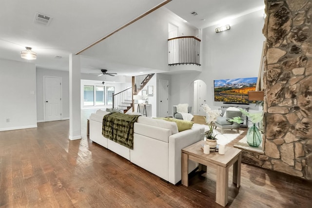 living room with a high ceiling, ceiling fan, and dark wood-type flooring