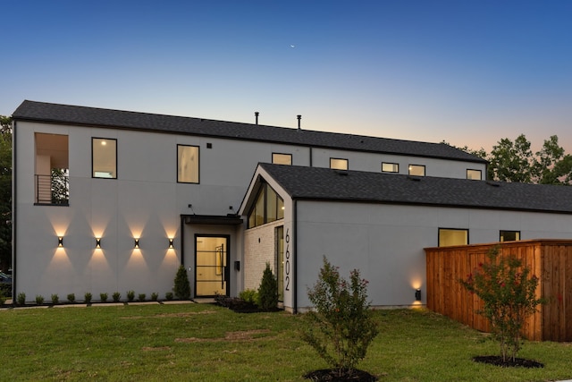 view of front of house with a yard, fence, and stucco siding