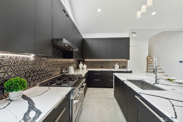 kitchen with decorative backsplash, high end stainless steel range oven, sink, wall chimney range hood, and hanging light fixtures