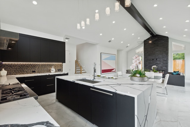 kitchen featuring tasteful backsplash, a spacious island, sink, lofted ceiling with beams, and decorative light fixtures