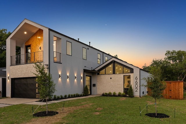 modern home with a garage, concrete driveway, a balcony, a front lawn, and brick siding