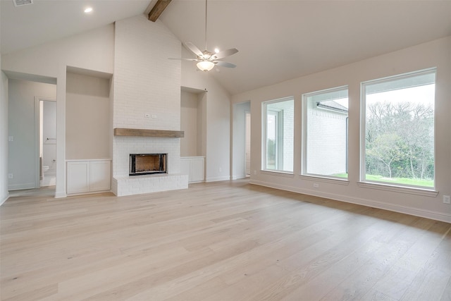 unfurnished living room featuring ceiling fan, beam ceiling, high vaulted ceiling, a brick fireplace, and light wood-type flooring