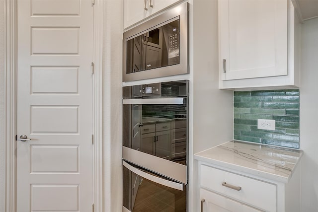 kitchen with tasteful backsplash, light stone countertops, stainless steel microwave, and white cabinets