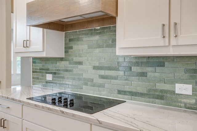 kitchen with white cabinets, black electric stovetop, tasteful backsplash, and light stone countertops