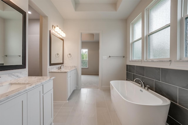 bathroom with plenty of natural light, vanity, a tub to relax in, and tile patterned floors