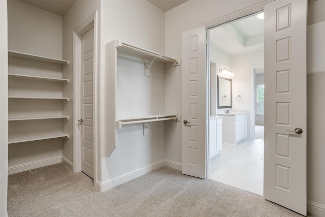 walk in closet featuring light colored carpet and sink