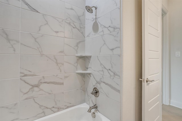 bathroom with wood-type flooring and tiled shower / bath