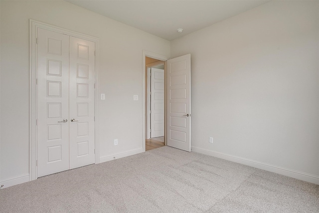 unfurnished bedroom with a closet and light colored carpet