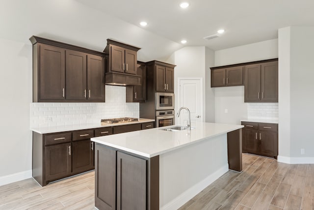 kitchen featuring tasteful backsplash, a center island with sink, sink, light hardwood / wood-style floors, and stainless steel appliances