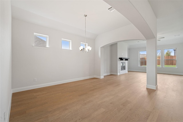 unfurnished living room featuring a chandelier and light hardwood / wood-style floors