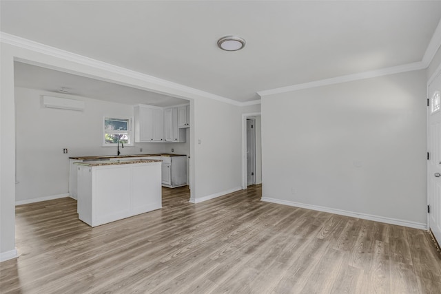 unfurnished living room featuring ornamental molding, a wall unit AC, and light hardwood / wood-style floors