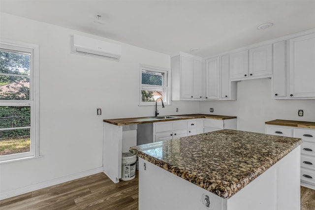 kitchen with sink, dark hardwood / wood-style floors, a kitchen island, white cabinetry, and a wall unit AC