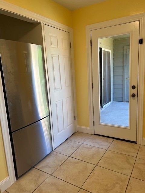 kitchen featuring light tile patterned flooring, baseboards, and freestanding refrigerator