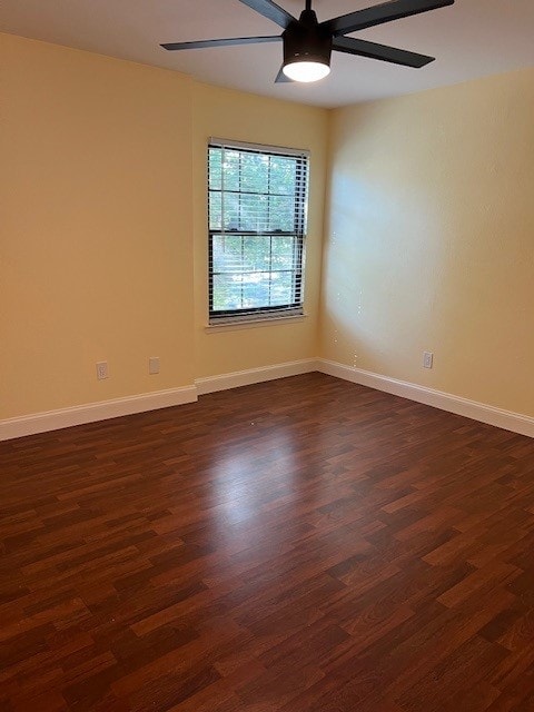 unfurnished room featuring dark wood-style floors, baseboards, and ceiling fan