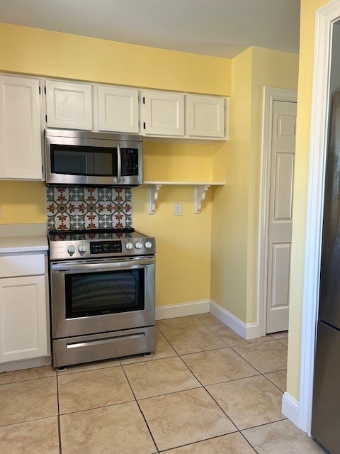 kitchen featuring white cabinetry, appliances with stainless steel finishes, light tile patterned flooring, light countertops, and baseboards