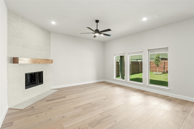 unfurnished living room with light hardwood / wood-style floors, a tile fireplace, and ceiling fan