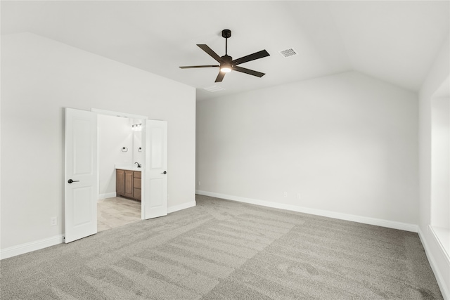 unfurnished bedroom with connected bathroom, lofted ceiling, light colored carpet, and ceiling fan