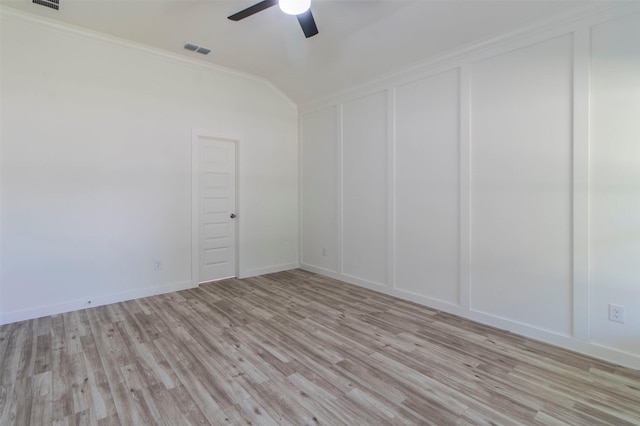 unfurnished room with visible vents, light wood-style flooring, crown molding, a decorative wall, and vaulted ceiling