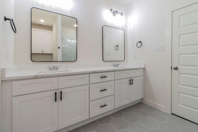 full bathroom featuring tile patterned floors, baseboards, double vanity, and a sink