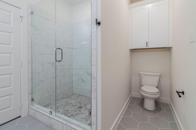full bath with tile patterned floors, a shower stall, toilet, and baseboards