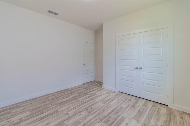 unfurnished bedroom featuring a closet, visible vents, light wood-style flooring, and baseboards