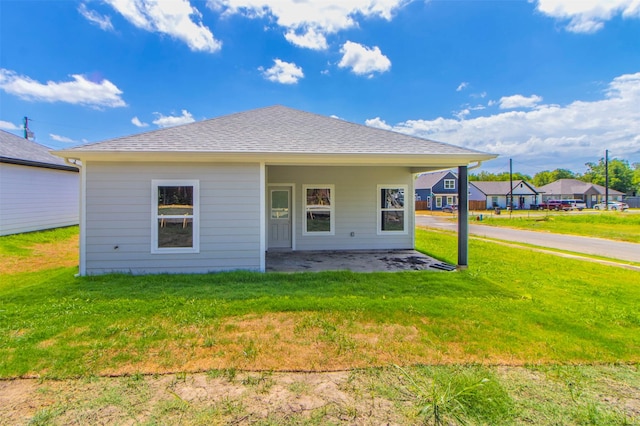 rear view of property with a lawn, a patio, and roof with shingles