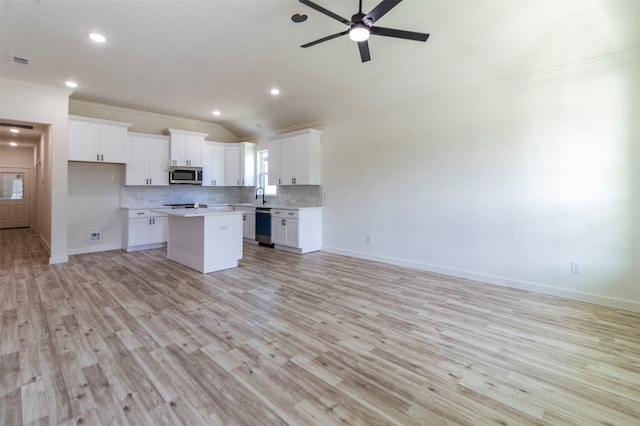 kitchen with white cabinets, dishwashing machine, light hardwood / wood-style flooring, and a kitchen island