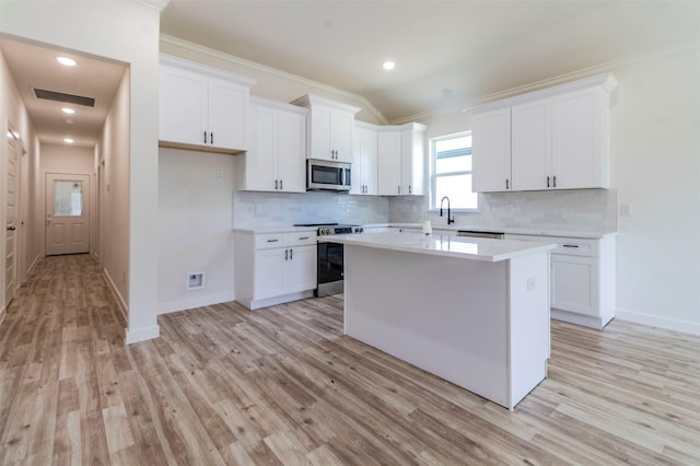 kitchen featuring visible vents, a kitchen island, stainless steel appliances, light countertops, and white cabinetry