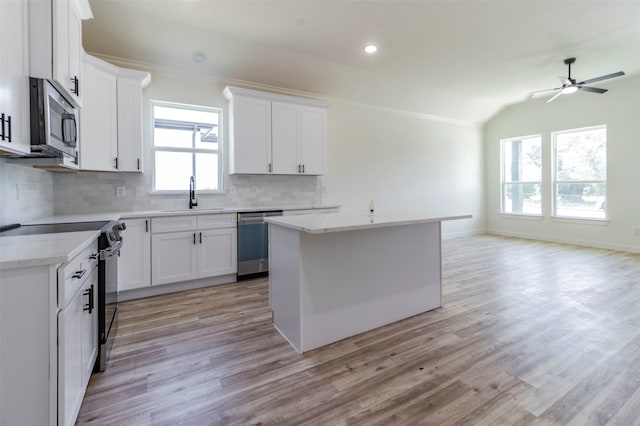 kitchen with decorative backsplash, light wood-type flooring, sink, a center island, and appliances with stainless steel finishes