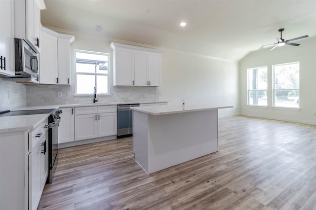 kitchen with light countertops, decorative backsplash, light wood-style flooring, stainless steel appliances, and a sink
