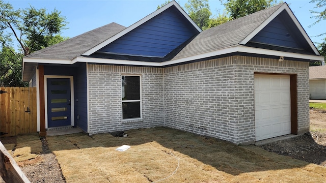 back of house featuring brick siding, fence, and roof with shingles