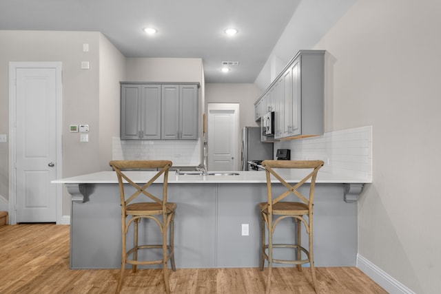 kitchen featuring a peninsula, light countertops, and gray cabinetry