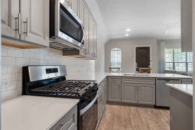 kitchen featuring gray cabinetry, sink, kitchen peninsula, and stainless steel appliances