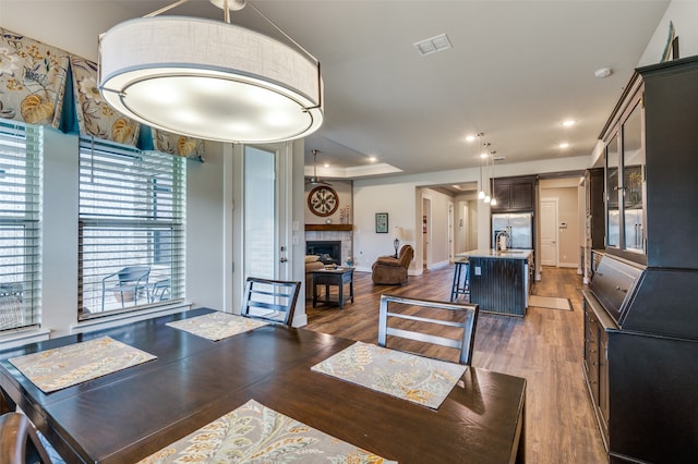 dining space featuring dark hardwood / wood-style floors, sink, and a tile fireplace