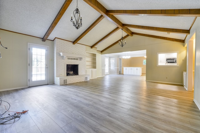 unfurnished living room with light wood-type flooring, built in shelves, a textured ceiling, and a brick fireplace