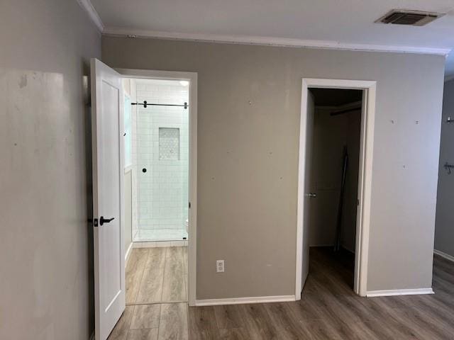 unfurnished bedroom featuring hardwood / wood-style floors, ensuite bathroom, a spacious closet, and a closet