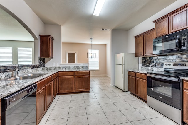 kitchen with backsplash, black appliances, sink, light tile patterned floors, and decorative light fixtures