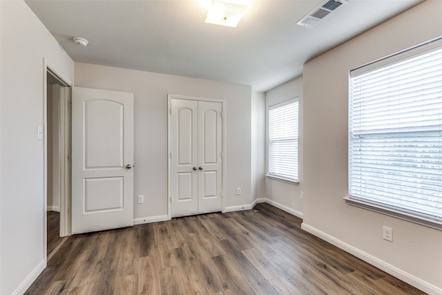 unfurnished bedroom with dark hardwood / wood-style flooring and a closet