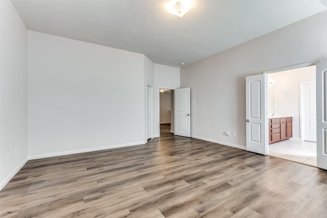 unfurnished bedroom featuring ensuite bath and hardwood / wood-style floors