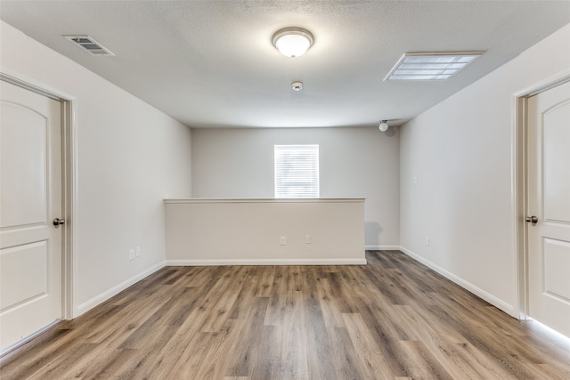 spare room featuring hardwood / wood-style flooring and a textured ceiling