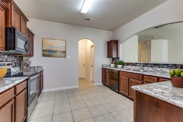 kitchen featuring light stone countertops, sink, tasteful backsplash, light tile patterned floors, and black appliances