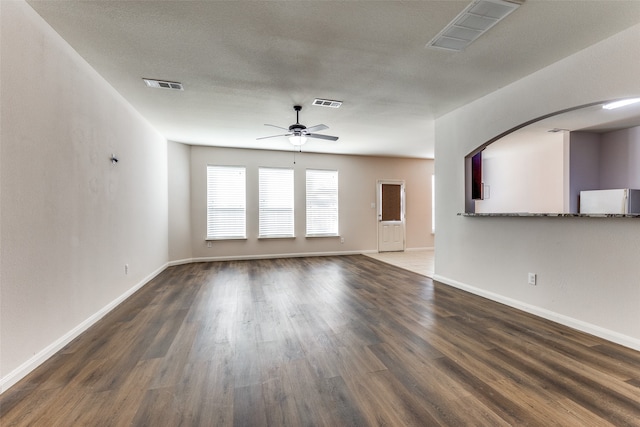 unfurnished living room with ceiling fan, dark hardwood / wood-style flooring, and a textured ceiling