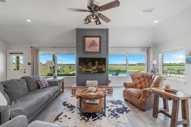 living room featuring ceiling fan, a fireplace, and light hardwood / wood-style flooring