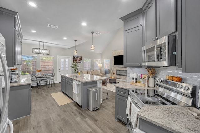 kitchen featuring gray cabinetry, stainless steel appliances, vaulted ceiling, and hanging light fixtures