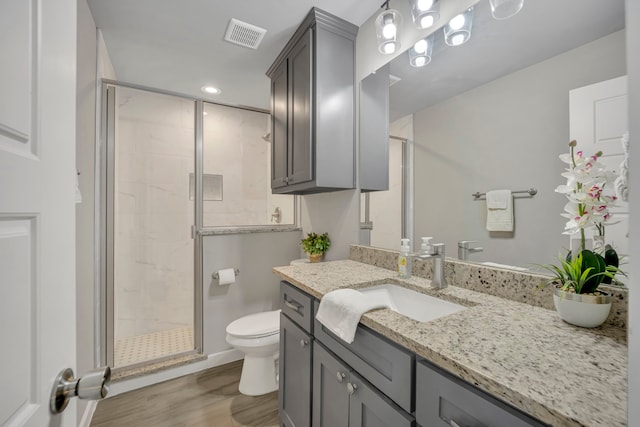 bathroom featuring toilet, hardwood / wood-style floors, a shower with shower door, and vanity