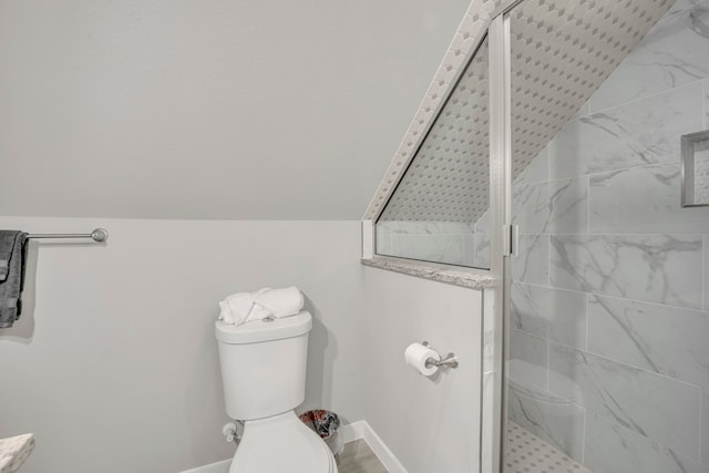 bathroom with vaulted ceiling, a shower with shower door, and toilet